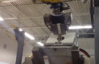 Robot removing a metal puck from an induction coil.