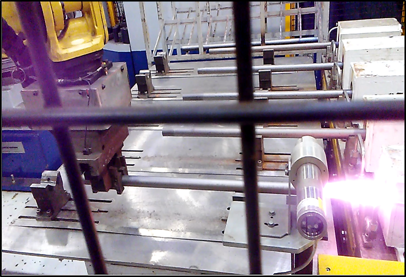 Robot inserting steel bar into induction coil prior to forging